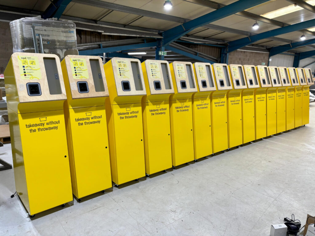 Metal kiosks powder coated yellow and assembled integrating non-sheet metal components such as plastics, wood, and graphics