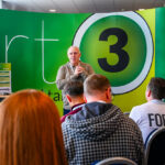 Photograph - Speaker at conference photographed over the heads of the audience