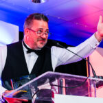 Photograph of excited on-stage presenter at evening event